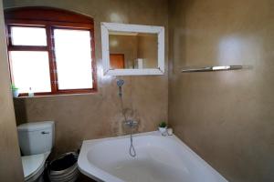 La salle de bains est pourvue d'une baignoire, de toilettes et d'un miroir. dans l'établissement Naude House In Struisbaai, à Struisbaai 20 autres photos