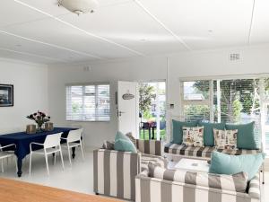Una sala de estar con sofás y una mesa de comedor. en Oorgenoeg In Arniston, en Arniston