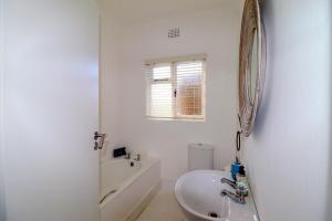 Un baño blanco con lavabo y espejo. en Oorgenoeg In Arniston, en Arniston 17 fotos más