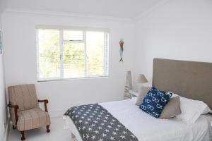 Un dormitorio con una cama y una silla y una ventana. en Oorgenoeg In Arniston, en Arniston