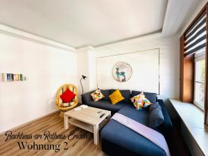a living room with a blue couch and a table at Bachhaus am Rathaus 2 in Emden +3 photos