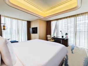 昆明市にあるWanda Vista Kunmingの大きなベッドと机があるホテルの部屋