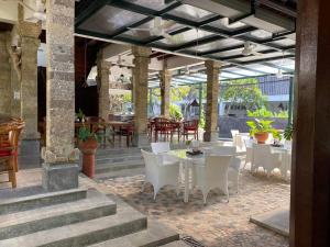 a patio with white tables and chairs and a table and chairs at Hotel Sari Bunga in Legian