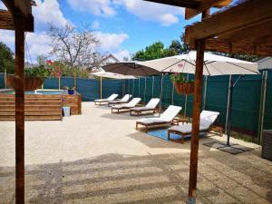 - un groupe de chaises longues et de parasols à côté de la piscine dans l'établissement R & R BERGERAC, à Bergerac