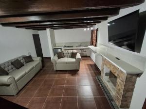 a living room with two couches and a flat screen tv at Cabañas De La Vega in Tomatlán