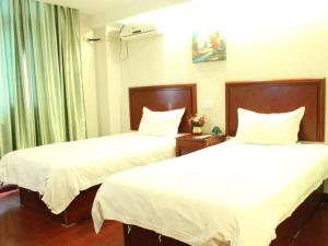 two beds in a hotel room with white sheets at GreenTree Inn Zhejiang Zhoushan Xincheng Business Hotel in Zhoushan
