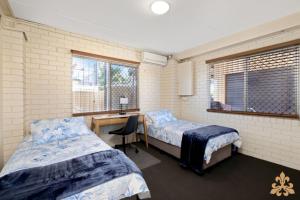 Habitación con 2 camas y escritorio. en Oasis On Rice Street Downstairs, en Rockhampton