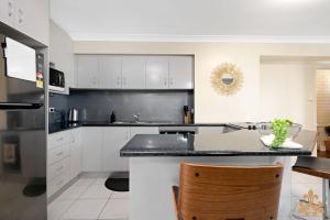Una cocina con gabinetes blancos y una encimera negra. en Oasis On Rice Street Downstairs, en Rockhampton