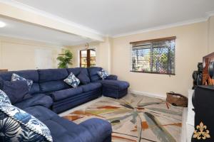 Una sala de estar con un sofá azul y una alfombra. en Oasis On Rice Street Downstairs, en Rockhampton