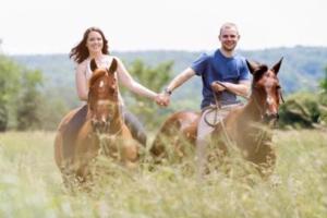 a man and a woman riding horses in a field at Hidden LakeFront Retreat in Sherburne