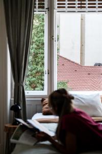 a girl laying on a bed reading a book at Frankie's Home in Budapest