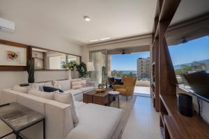 a living room with white furniture and a large window at Luxury Beachfront Apartment in Cabo in Cabo San Lucas