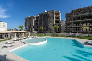 a large swimming pool with chairs and a building at Luxury Beachfront Apartment in Cabo in Cabo San Lucas