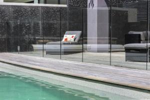 a swimming pool next to a building with a chair next to a mirror at Tyrone Beachside Luxury - Home Theatre Study in Rye
