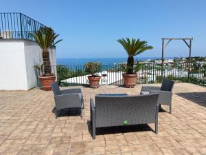 a patio with chairs and palm trees and the ocean at Chez Marie Ischia in Forio d'Ischia