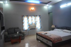 a bedroom with a bed and a couch and a window at Hotel Naveen Residency in Darbhanga