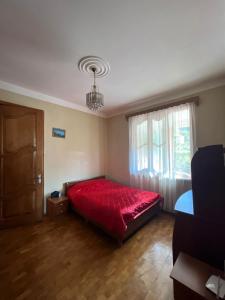 a bedroom with a red bed and a window at Home in paradise in Tofaloglebi