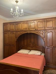 a bed with a wooden head board and a chandelier at Home in paradise in Tofaloglebi