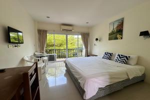 a bedroom with a bed and a desk and a window at Choengmon Residence in Choeng Mon Beach