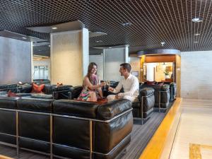 a man and a woman sitting on a leather couch at H&ocirc;tel Lyon M&eacute;tropole in Lyon