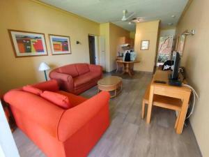 a living room with a red couch and a television at Brookes Hill 1 Bedroom in Summerstrand +10 photos