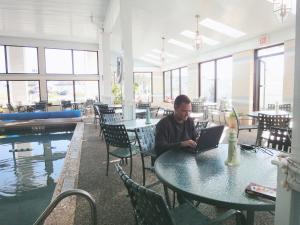 un homme assis à une table avec un ordinateur portable dans l'établissement Hyannis Travel Inn, à Hyannis