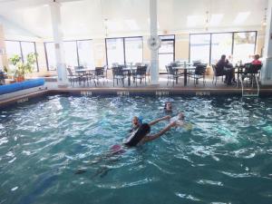 Dos personas están nadando en una piscina en Hyannis Travel Inn en Hyannis