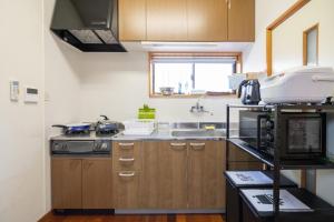 eine Küche mit Holzschränken und einer Spüle in der Unterkunft Rise's House in Nishio