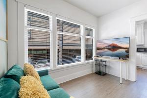 a living room with a green couch and two windows at Vintage 3 Bedroom Home in Prime Eastlake Seattle with Private Parking in Seattle