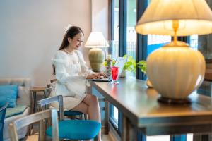 a woman sitting at a desk with a laptop at Bhukitta Boutique Hotel Phuket Town in Phuket Town
