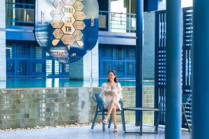 普吉镇Bhukitta Boutique Hotel Phuket Town的坐在椅子上的穿着白色衣服的女人