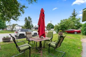 a table with chairs and a red umbrella on the grass at Stylish Studio Suite Near Downtown in Anchorage