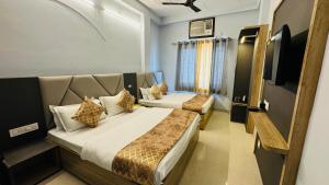 a hotel room with two beds and a tv at Hotel City Palace in Varanasi