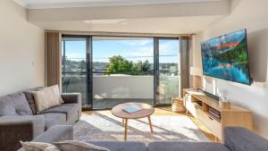 a living room with a couch and a tv at Husky Oasis - Centre OF Huskisson - in Huskisson