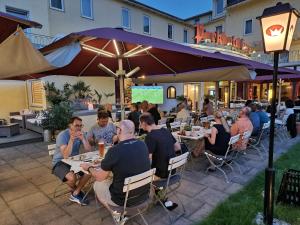 a group of people sitting at tables under an umbrella at Parkhotel Krone in Bensheim