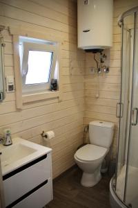 a bathroom with a toilet and a sink and a window at Domki SILVER 3 in Jarosławiec