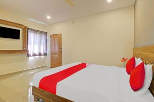 Un dormitorio con una cama grande con almohadas rojas y blancas. en Hotel O R Square, en Warangal