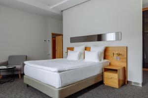 una camera da letto con un grande letto bianco e una sedia di Old Ijevan Boutique Hotel a Ijevan