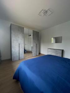1 Schlafzimmer mit einem blauen Bett und einem Badezimmer in der Unterkunft LA TERRAZZA - Very Quiet - Free park - 3 min from Varese center and lake - AIR Conditioning - Cycling friendly in Varese