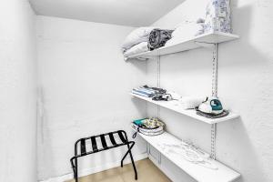 a white room with white shelves and a black chair at Hallandale Mins From Beach & Aventura Mall Hn01 in Hallandale Beach