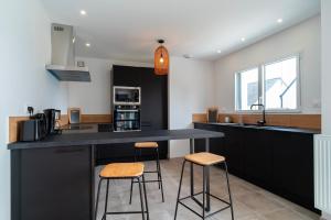 a kitchen with a black counter and two stools at La Villa Bianca - A 10 min à pied de la plage in Bénodet +6 photos