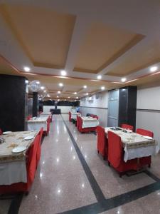 a dining room with tables and red chairs at Hotel Metro Inn in Ajmer