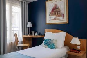 a hotel room with a bed and a blue wall at Grand Hotel Du Calvados in Paris