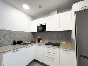 a white kitchen with white cabinets and a sink at El Salvador 53 in Las Palmas de Gran Canaria