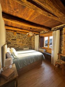 a bedroom with a bed and a stone wall at Lar da cima in Folgoso +91 photos