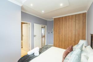 a bedroom with a large white bed and wooden cabinets at Endless Summer Coastal Condo in Summerstrand