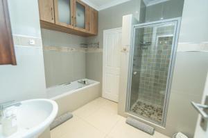 a bathroom with a shower and a sink and a tub at Endless Summer Coastal Condo in Summerstrand +25 photos