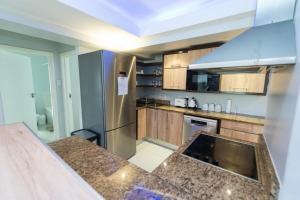 a kitchen with wooden cabinets and a stainless steel refrigerator at The Pearls 2nd Floor Luxury Apartment in Port Elizabeth +21 photos