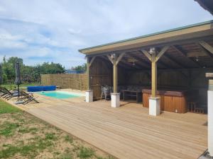 a wooden deck with a swimming pool and a pavilion at A Svájci Portája in Tiszadada
