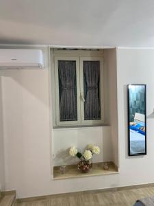 a room with a window with a vase of flowers on a shelf at La Petite Maison in Naples